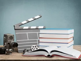 Klaps filmowy i książki ułożone na biurku