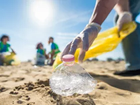 Dłoń podnosząca zgniecioną plastikową butelką