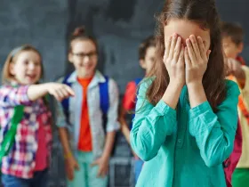 Dziewczynka wytykana palcami przez równieśników