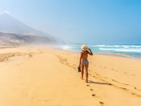 Kobieta idąca po nadmorskiej plaży