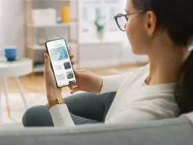 Kobieta siedząca na kanapie ogląda wiadomości na smartfonie
