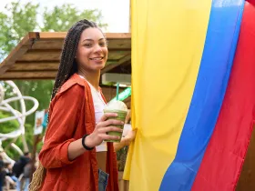 Kobieta ze trzyma smoothie na tle kolumbijskiej flagi