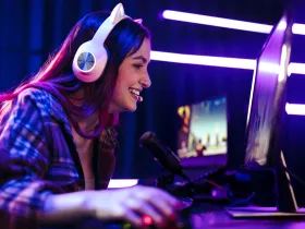 Uśmiechnięta gamerka w słuchawkach z kocimi uszami, grająca w grę komputerową