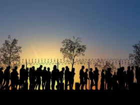 Migranci stojący pod ogrodzeniem