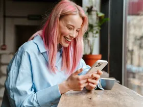 Uśmiechnięta kobieta trzymająca w dłoniach smartfona