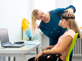 Kobieta zakłada dziewczynce na czoło opaskę do badania Biofeedback/EEG