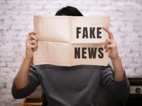 Człowiek czytający gazetę z napisem „Fake news
