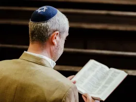 Żyd w jarmułce czyta świętą księgę w synagodze