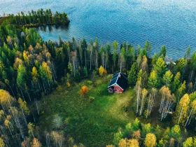 Czerwony domek pośród drzew na brzegu jeziora w Finlandii 