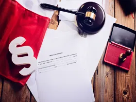 Na biurku: złożona flaga polski, paragraf, młotek sędziego i dokument „Prośba o ułaskawienie”
