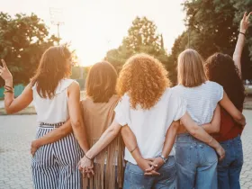 Grupa kobiet trzyma się za dłonie spacerując