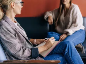  Uważny terapeuta w okularach robi notatki podczas sesji z klientem